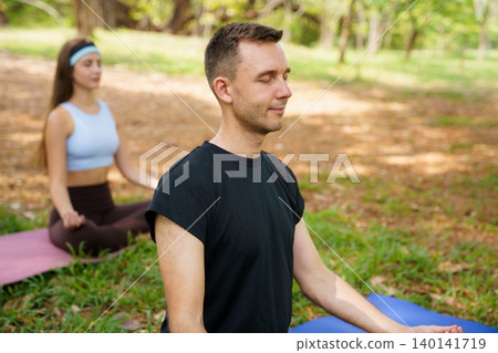 Young man and woman practicing yoga and meditation in green park Young man and woman practicing yoga and meditation in green park 140141719
