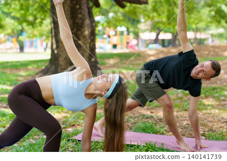 Morning wellness session with couple performing yoga in nature Morning wellness session with couple performing yoga in nature 140141739