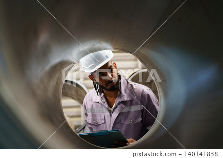 Young hispanic engineer inspecting metal roll in factory 140141838