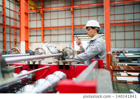 Industrial worker inspecting machineries with holding clipboard and walkie talkie 140141841