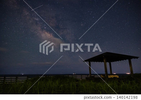 由銀河和涼亭輪廓交織而成的星空海濱風景。 由銀河和涼亭輪廓交織而成的星空海濱風景。 140142198