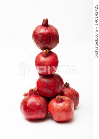 Ripe red pomegranates on a white background Ripe red pomegranates on a white background 140142425
