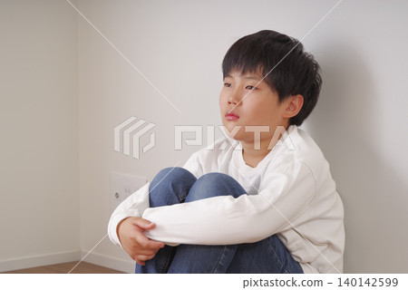 一個男孩,他面無表情的臉上隱隱透露出痛苦。 一個男孩,他面無表情的臉上隱隱透露出痛苦。 140142599