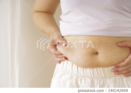 A woman who is concerned about her belly fat A woman who is concerned about her belly fat 140142609