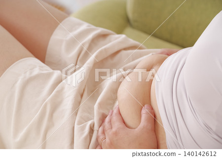 A woman who is concerned about her belly fat A woman who is concerned about her belly fat 140142612