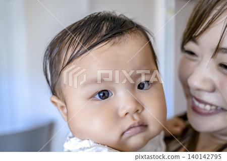 一位微笑的母親抱著嬰兒。 140142795