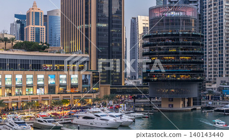 Aerial view of Dubai Marina with shopping mall, restaurants, towers and yachts day to night timelapse, United Arab Emirates. 140143440