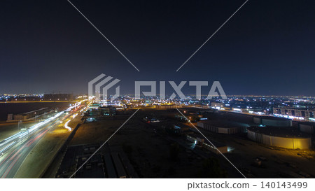 Traffic on a big road junction in Ajman aerial view from rooftop at night timelapse. 140143499