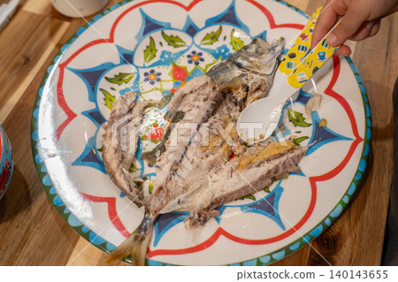 A three-year-old desperately trying to detach grilled horse mackerel. A three-year-old desperately trying to detach grilled horse mackerel. 140143655
