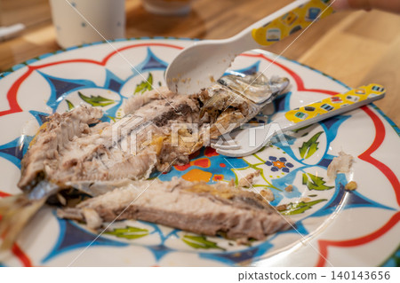 A three-year-old child desperately trying to break apart a grilled horse mackerel. A three-year-old child desperately trying to break apart a grilled horse mackerel. 140143656
