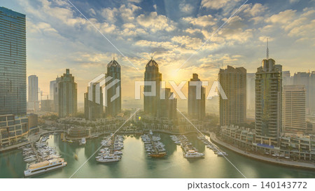 View of modern skyscrapers shining in sunrise lights timelapse in Dubai Marina in Dubai, UAE. View of modern skyscrapers shining in sunrise lights timelapse in Dubai Marina in Dubai, UAE. 140143772