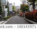 A spring scene of an elderly person walking with a walker down a street in a residential area where cherry blossoms are in bloom. 140143971