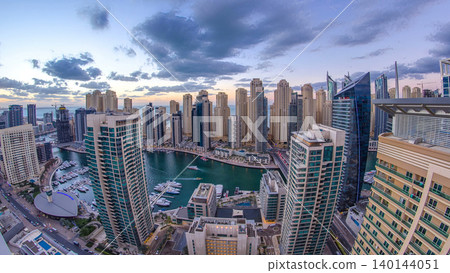 Modern skyscrapers and water channel with boats of Dubai Marina at sunset and day to night timelapse, United Arab Emirates. 140144051