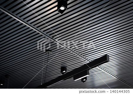Bottom view of lath ceiling with spot lights. Abstract modern architecture or interior background in black and white with geometric structure. Bottom view of lath ceiling with spot lights. Abstract modern architecture or interior background in black and white with geometric structure. 140144305