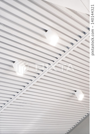 Ceiling with bright lights in a modern warehouse, shopping center building, office or commercial real estate object. Directional LED lights on rails under the ceiling Ceiling with bright lights in a modern warehouse, shopping center building, office or commercial real estate object. Directional LED lights on rails under the ceiling 140144321