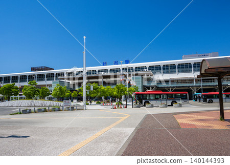 A view of Niigata Station's modern station building and station square under a clear blue sky. A view of Niigata Station's modern station building and station square under a clear blue sky. 140144393