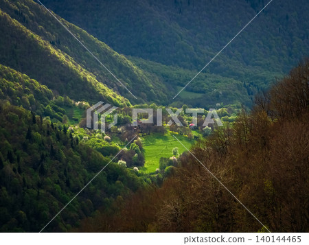 Sunlit valley nestled between rugged hills Sunlit valley nestled between rugged hills 140144465
