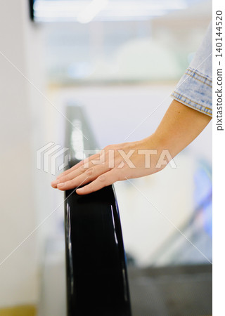 Customer Holding Handrail on Moving Escalator Rail Customer Holding Handrail on Moving Escalator Rail 140144520