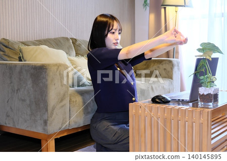 一位女士在遠距工作間隙做伸展運動,放鬆身心。 一位女士在遠距工作間隙做伸展運動,放鬆身心。 140145895