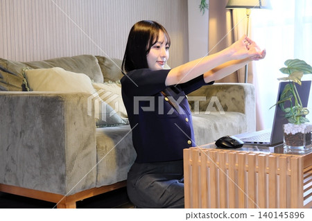 A woman refreshes herself with stretches during a break from remote work. A woman refreshes herself with stretches during a break from remote work. 140145896