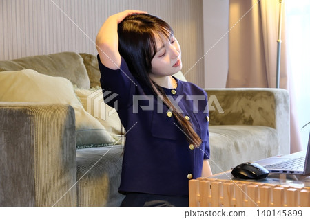 A woman refreshes herself with stretches during a break from remote work. A woman refreshes herself with stretches during a break from remote work. 140145899