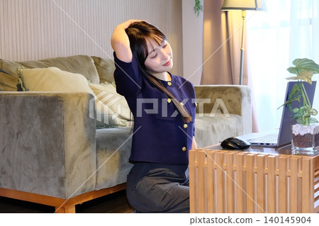 A woman refreshes herself with stretches during a break from remote work. 140145904