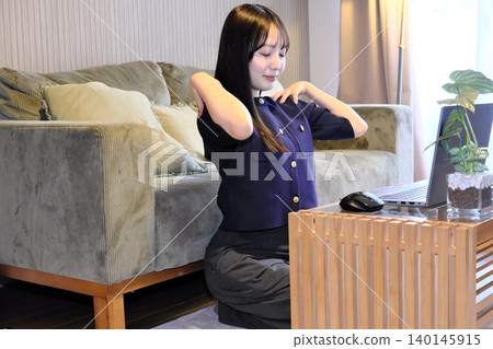 A woman refreshes herself with stretches during a break from remote work. A woman refreshes herself with stretches during a break from remote work. 140145915