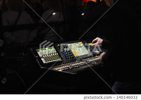 Live sound engineer adjusts a digital mixing console Live sound engineer adjusts a digital mixing console 140146032