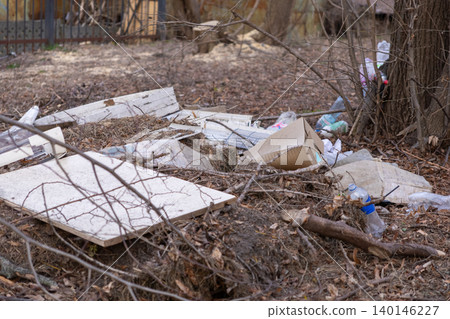 Discarded wooden debris and plastic bottles abandoned in an overgrown forest area, highlighting environmental pollution and the urgent need for nature conservation and waste control Discarded wooden debris and plastic bottles abandoned in an overgrown forest area, highlighting environmental pollution and the urgent need for nature conservation and waste control 140146227
