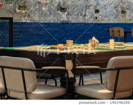 A vintage pool table is repurposed as a dining area in a rustic industrial loft with cream chairs for a unique creative cafe atmosphere that blends leisure with urban interior style A vintage pool table is repurposed as a dining area in a rustic industrial loft with cream chairs for a unique creative cafe atmosphere that blends leisure with urban interior style 140146260