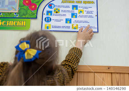 School child pointing at a human rights poster on a classroom wall, depicting an educational scene of learning about children welfare and social equality in a modern primary school School child pointing at a human rights poster on a classroom wall, depicting an educational scene of learning about children welfare and social equality in a modern primary school 140146290