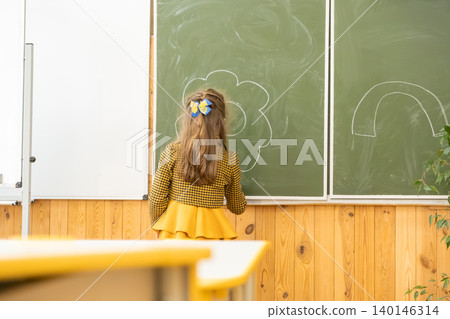 A young girl draws a bright flower with white chalk on a green classroom board to illustrate academic creativity and childhood learning moments in a sunny school environment A young girl draws a bright flower with white chalk on a green classroom board to illustrate academic creativity and childhood learning moments in a sunny school environment 140146314