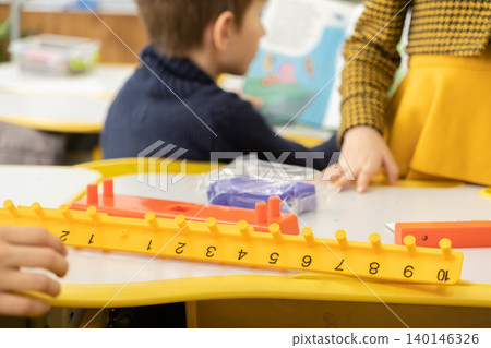 Children working with colorful math counting sticks on a classroom table to practice elementary arithmetic concepts while engaging in collaborative group learning during school lessons Children working with colorful math counting sticks on a classroom table to practice elementary arithmetic concepts while engaging in collaborative group learning during school lessons 140146326