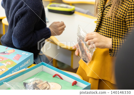 Students interact with an anatomy magnet game at their school desk, exploring human biology concepts through hands-on educational activities in a bright and creative classroom 140146330
