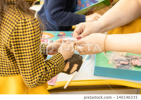 A teacher helps a young child with educational puzzle pieces at a classroom desk, highlighting hands-on learning activities during a creative lesson for school kids today A teacher helps a young child with educational puzzle pieces at a classroom desk, highlighting hands-on learning activities during a creative lesson for school kids today 140146335