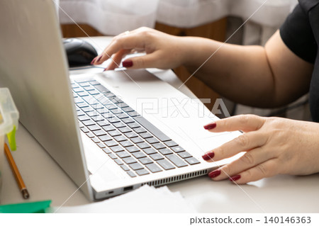 A person typing on a laptop at a bright home desk captures a sense of professional efficiency and focused digital productivity within a comfortable and modern remote working space A person typing on a laptop at a bright home desk captures a sense of professional efficiency and focused digital productivity within a comfortable and modern remote working space 140146363