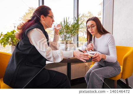 Calm and focused collaboration between women with vision during a mid-day cafe meeting. Concept of digital innovation and business development. Mid shot Calm and focused collaboration between women with vision during a mid-day cafe meeting. Concept of digital innovation and business development. Mid shot 140146472