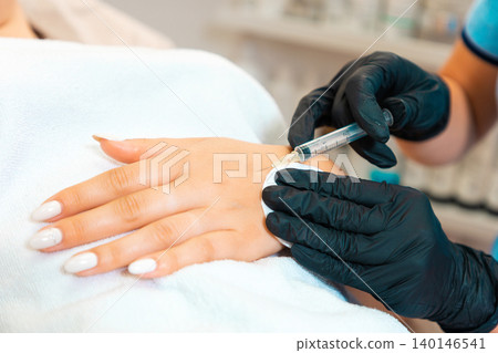 Cosmetologist makes injections of botulinum toxin on the client's hand against hyperhidrosis. Close up. Procedure in beauty salon Cosmetologist makes injections of botulinum toxin on the client's hand against hyperhidrosis. Close up. Procedure in beauty salon 140146541