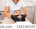 Spa and beauty procedure. Professional cosmetologist gives a facial massage to the client in salon. Close up. Concept of cosmetology and lifting 140146549