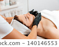 Spa. Professional cosmetologist gives a facial massage to the client in salon. Close up. View from the shoulders. Concept of lifting and beauty procedures 140146553