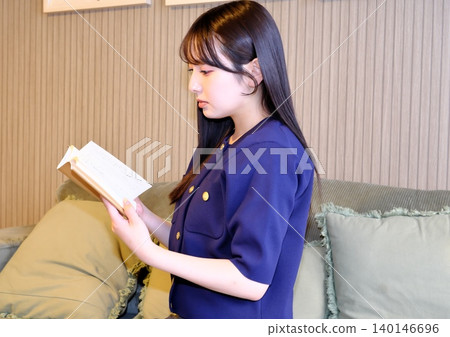 A blissful indoor holiday. Enjoying a book while bathed in soft light—a sophisticated adult relaxation time. A blissful indoor holiday. Enjoying a book while bathed in soft light—a sophisticated adult relaxation time. 140146696