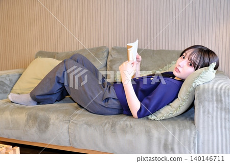 A blissful indoor holiday. Enjoying a book while bathed in soft light—a sophisticated adult relaxation time. A blissful indoor holiday. Enjoying a book while bathed in soft light—a sophisticated adult relaxation time. 140146711