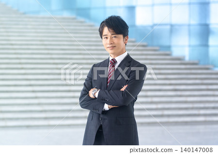 一位身穿西裝的日本商人面帶微笑,雙手交叉抱在胸前。 一位身穿西裝的日本商人面帶微笑,雙手交叉抱在胸前。 140147008