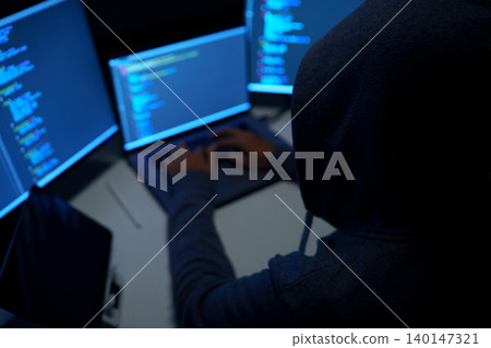 Hacker Working at Multiple Monitors in Dark Room Hacker Working at Multiple Monitors in Dark Room 140147321