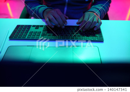 Hands Typing on Keyboard Under Neon Light Hands Typing on Keyboard Under Neon Light 140147341