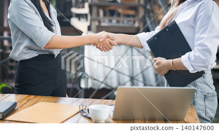 Two asian female architect and engineer in protective helmets shaking hands after meeting. Success collaboration concept. Two asian female architect and engineer in protective helmets shaking hands after meeting. Success collaboration concept. 140147600