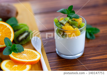 creamy yogurt dessert with kiwi and orange on wooden background creamy yogurt dessert with kiwi and orange on wooden background 140147751