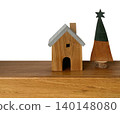 Wooden miniature house and decorative tree on a wooden table against a white background. Rustic home decor concept with copy space. 140148080