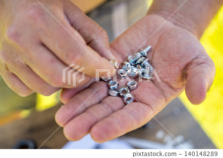 Hands holding screws and nuts for DIY assembly close up Hands holding screws and nuts for DIY assembly close up 140148289