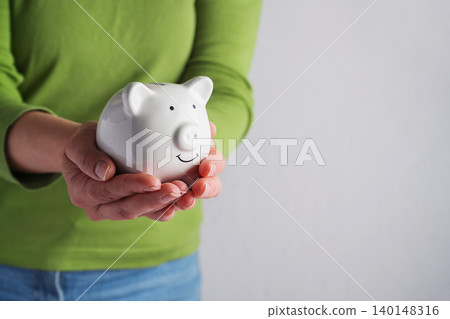 Person holding piggy bank in hands, savings personal finance financial security and money management concept Person holding piggy bank in hands, savings personal finance financial security and money management concept 140148316